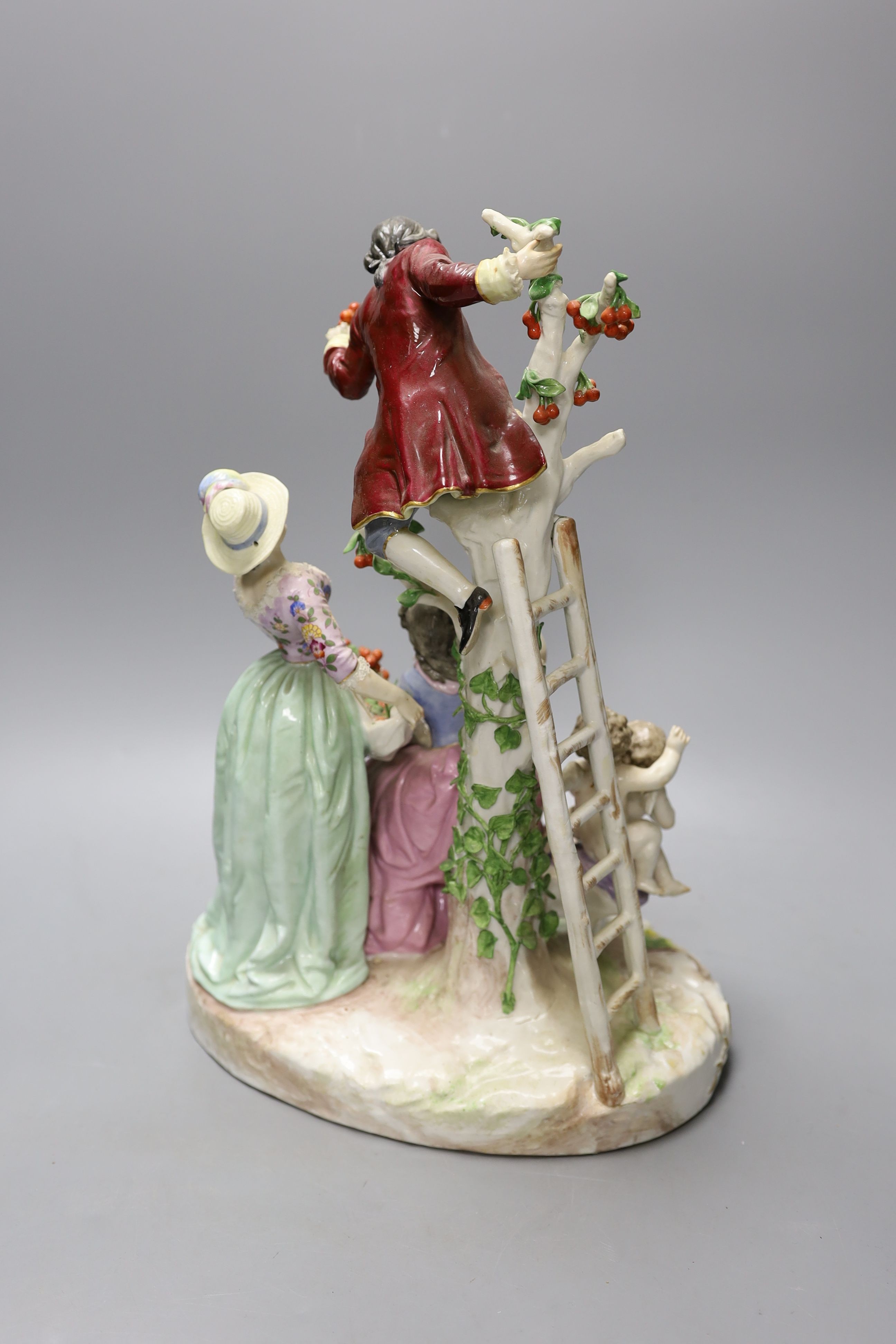 A large German porcelain group of figures picking fruit from a tree, 37cm